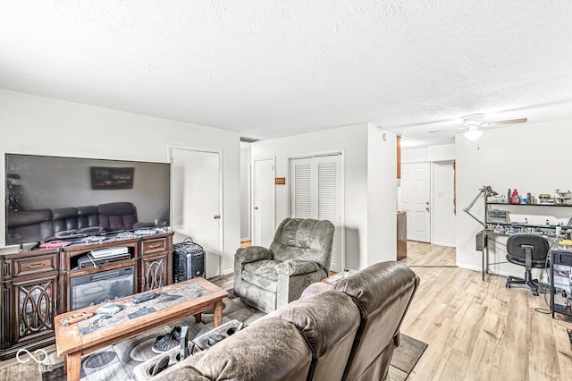 living room with ceiling fan, light hardwood / wood-style flooring, and a textured ceiling