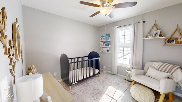 bedroom with a nursery area and ceiling fan