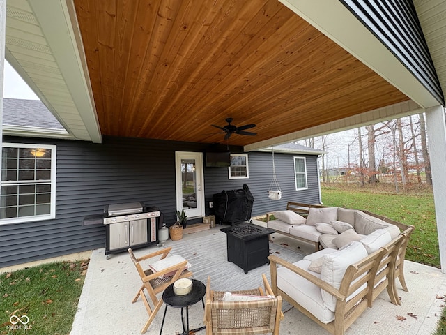 view of patio with area for grilling, an outdoor living space with a fire pit, and ceiling fan