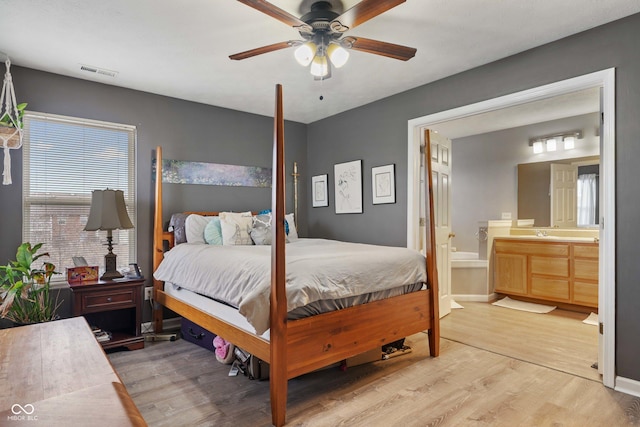 bedroom featuring ensuite bathroom, ceiling fan, and light wood-type flooring