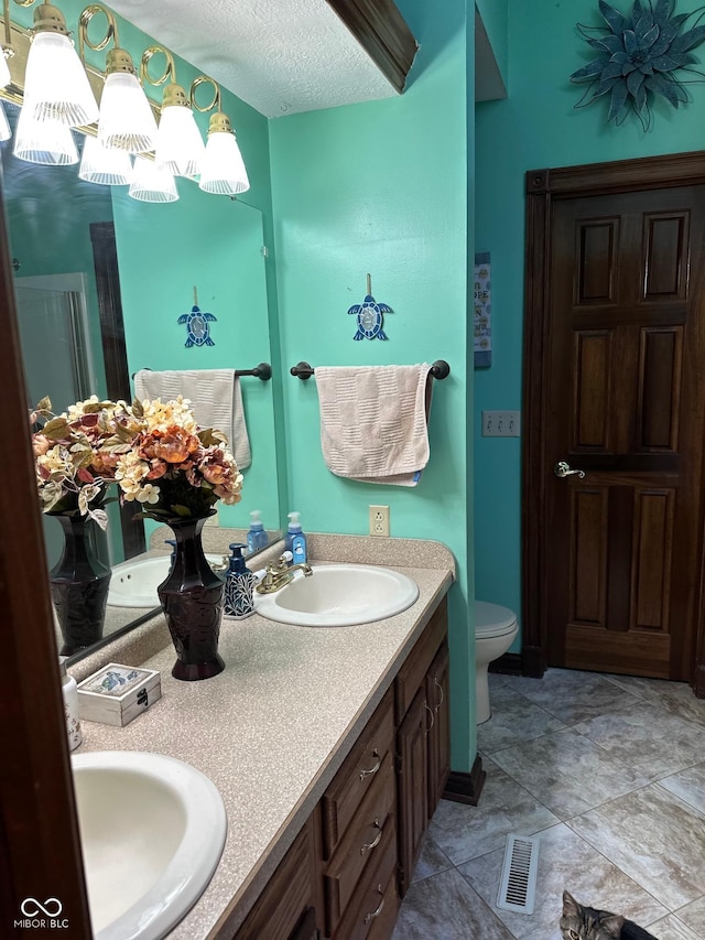 bathroom with vanity, toilet, and a textured ceiling