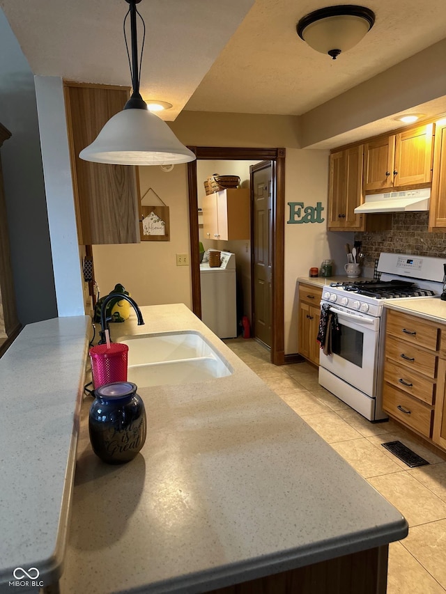 kitchen featuring pendant lighting, washer / clothes dryer, sink, backsplash, and white range with gas stovetop