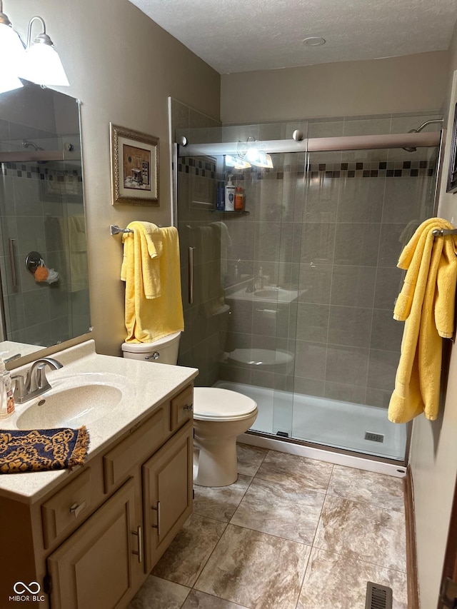 bathroom with vanity, an enclosed shower, a textured ceiling, and toilet