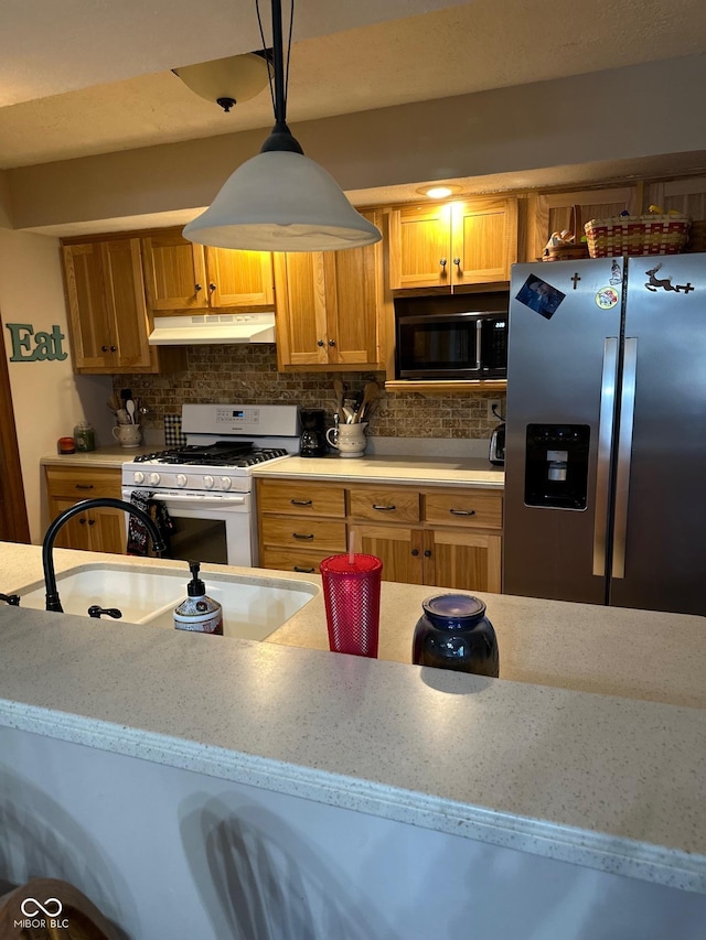 kitchen featuring sink, stainless steel fridge, white gas range oven, tasteful backsplash, and decorative light fixtures