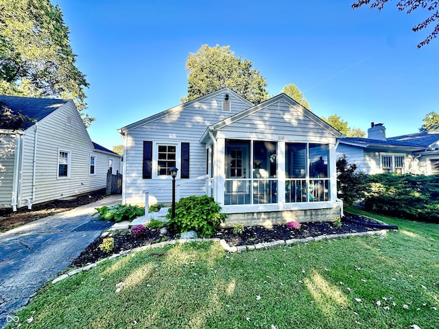 view of front facade with a front lawn and a sunroom