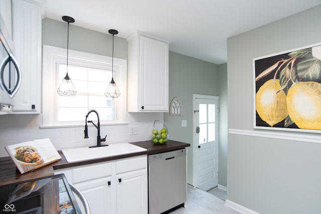 kitchen with pendant lighting, sink, dishwasher, white cabinetry, and decorative backsplash