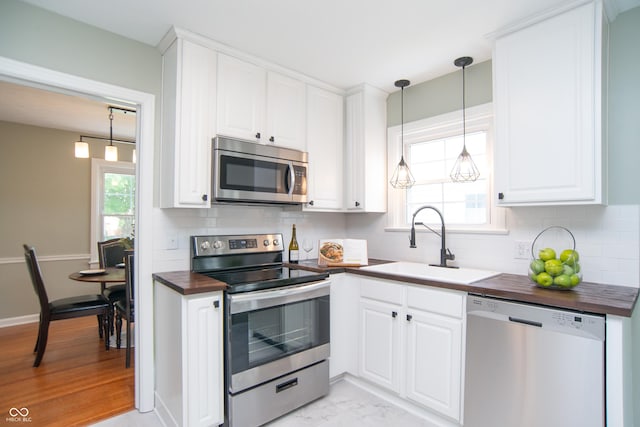 kitchen with sink, white cabinetry, wooden counters, appliances with stainless steel finishes, and a healthy amount of sunlight