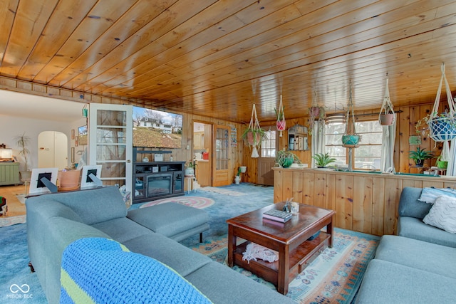 carpeted living room with wooden ceiling, wooden walls, and a fireplace