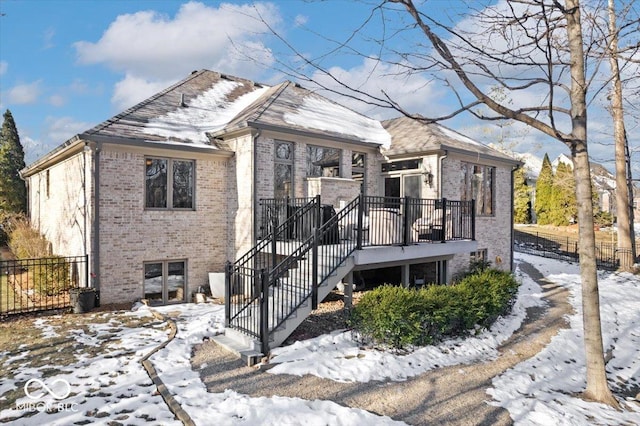 view of front of property featuring stairs, fence, and brick siding