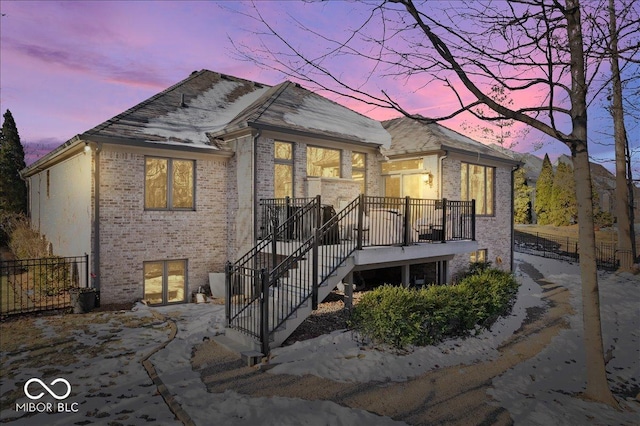 view of front of property featuring stairway, fence, and brick siding