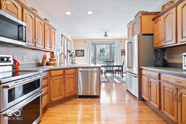 kitchen featuring a sink, stainless steel appliances, brown cabinets, and light wood finished floors