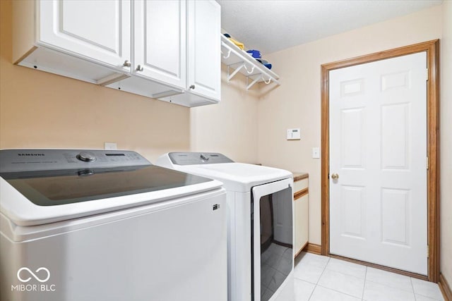 clothes washing area with cabinet space, light tile patterned floors, washer and dryer, and a textured ceiling