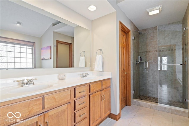 full bath featuring a sink, double vanity, a stall shower, and tile patterned floors