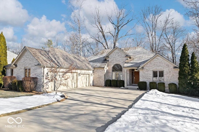 french country style house with brick siding, concrete driveway, and a garage