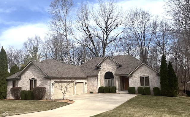 french country style house featuring concrete driveway, a garage, brick siding, and a front yard