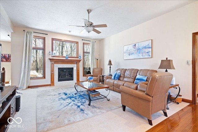 living area featuring a wealth of natural light, baseboards, ceiling fan, and a high end fireplace