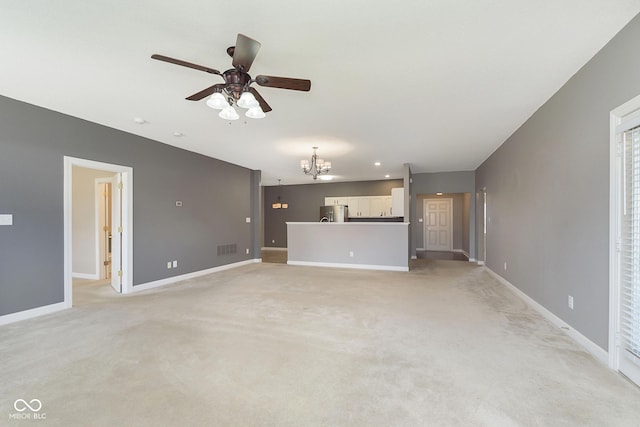 unfurnished living room featuring ceiling fan with notable chandelier and light carpet