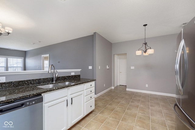 kitchen featuring sink, appliances with stainless steel finishes, white cabinetry, an inviting chandelier, and dark stone counters