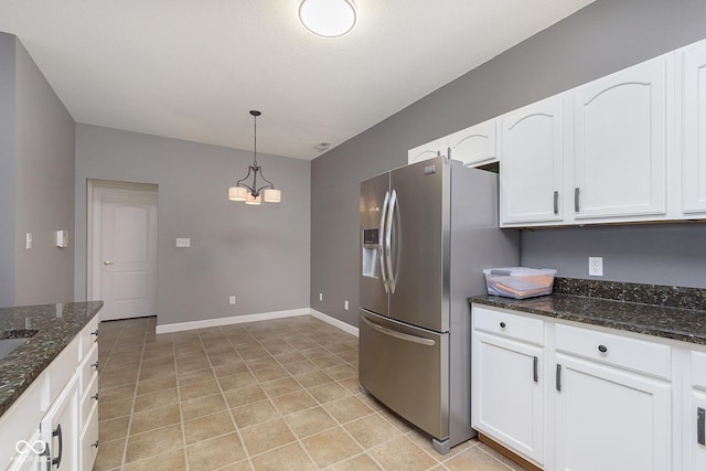 kitchen featuring pendant lighting, dark stone countertops, stainless steel fridge with ice dispenser, and white cabinets