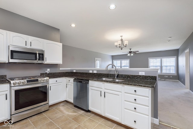 kitchen featuring sink, dark stone countertops, kitchen peninsula, stainless steel appliances, and white cabinets