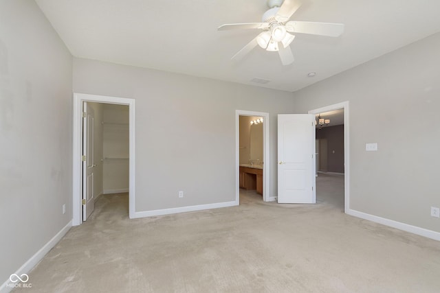 unfurnished bedroom with ensuite bathroom, a spacious closet, light colored carpet, ceiling fan, and a closet