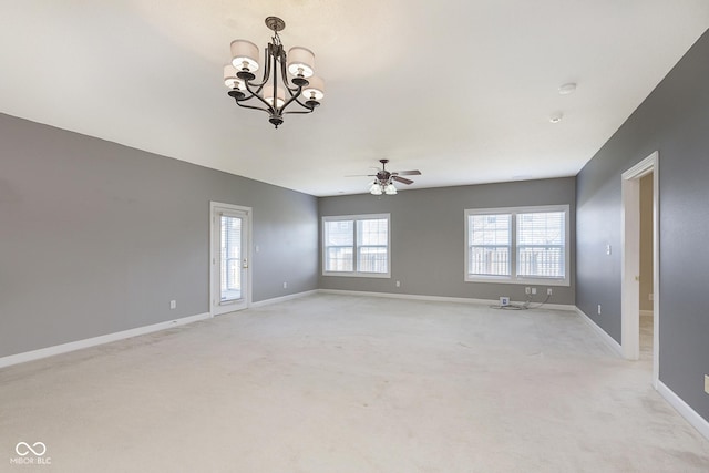 carpeted empty room featuring ceiling fan with notable chandelier