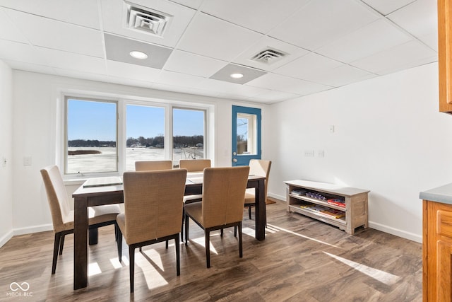 dining space with a drop ceiling and hardwood / wood-style flooring