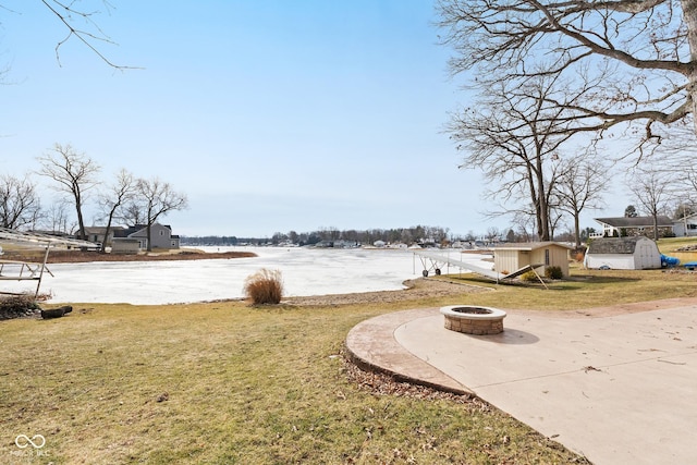 view of yard featuring a shed, a fire pit, and a water view