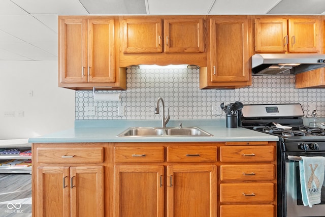 kitchen with stainless steel range with gas cooktop, sink, wall chimney range hood, and decorative backsplash