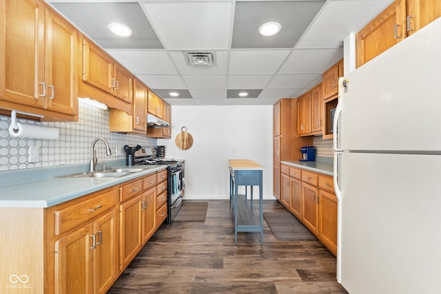 kitchen with stainless steel gas range, sink, white refrigerator, dark hardwood / wood-style floors, and decorative backsplash