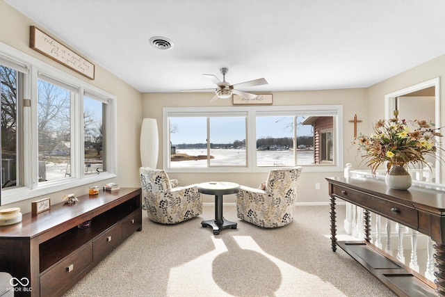 living area featuring plenty of natural light, ceiling fan, and carpet