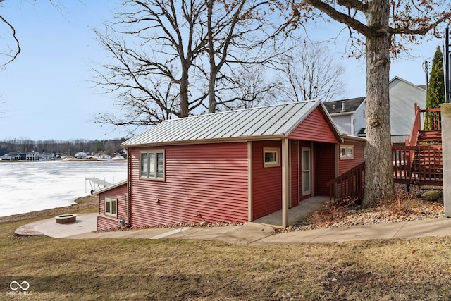 view of side of property with a fire pit, a water view, and a lawn