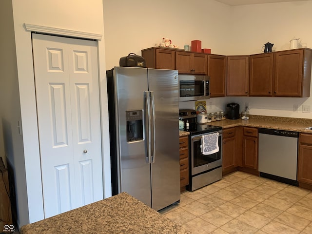 kitchen with appliances with stainless steel finishes, light tile patterned floors, and light stone counters