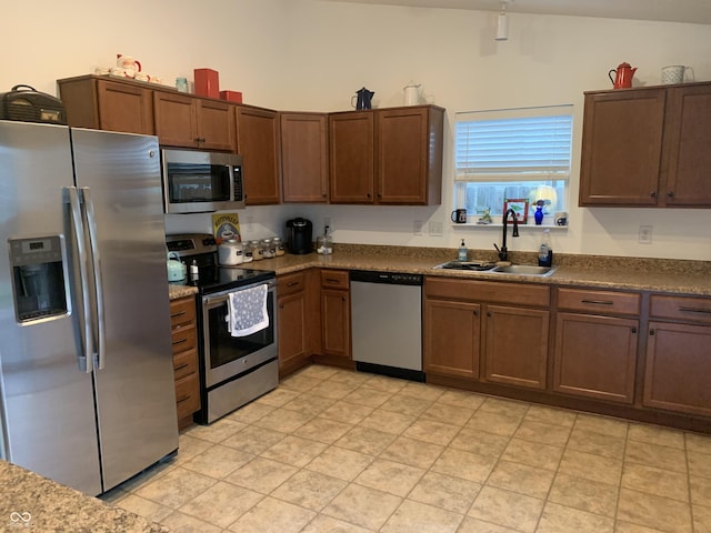 kitchen with vaulted ceiling, appliances with stainless steel finishes, and sink