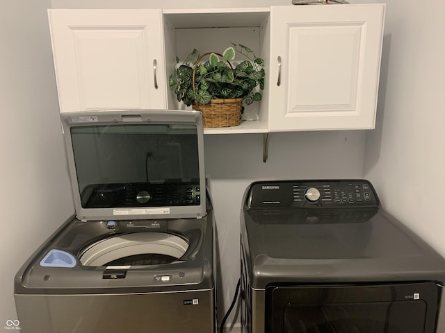 laundry room with separate washer and dryer and cabinets