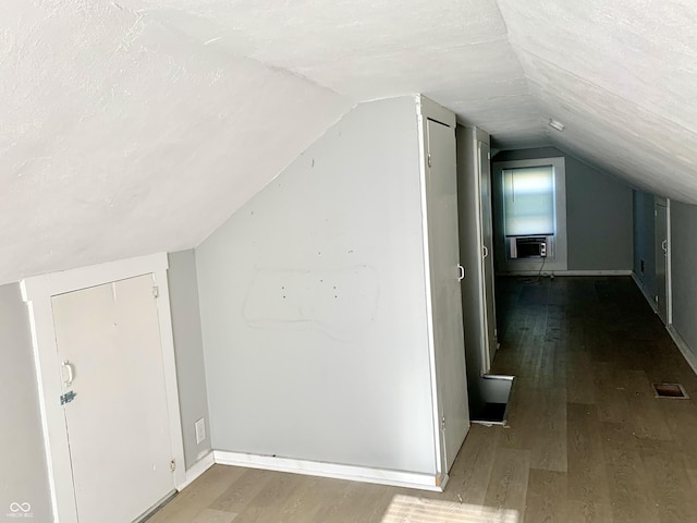 bonus room with cooling unit, lofted ceiling, hardwood / wood-style floors, and a textured ceiling