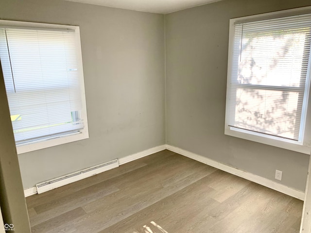 unfurnished room with hardwood / wood-style floors and a baseboard heating unit