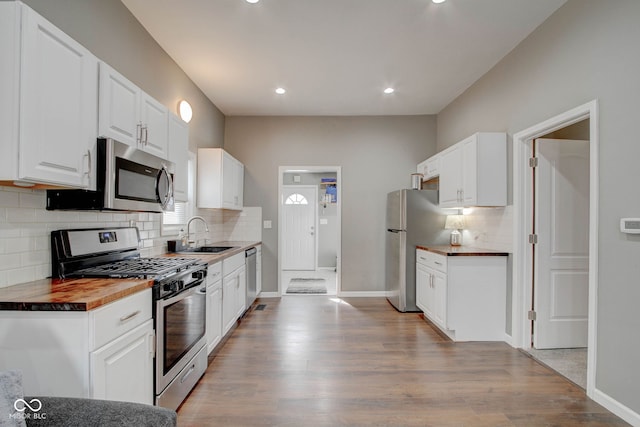 kitchen with sink, wooden counters, appliances with stainless steel finishes, white cabinetry, and light wood-type flooring