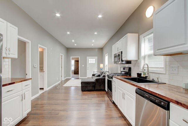 kitchen with butcher block counters, sink, white cabinetry, and stainless steel appliances