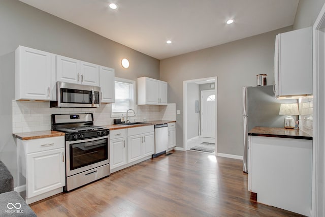 kitchen featuring stainless steel appliances, sink, white cabinets, and wood counters