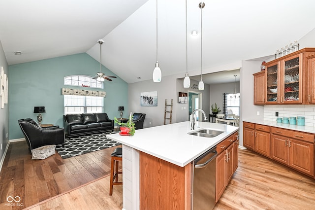 kitchen featuring a breakfast bar, sink, a center island with sink, light wood-type flooring, and stainless steel dishwasher