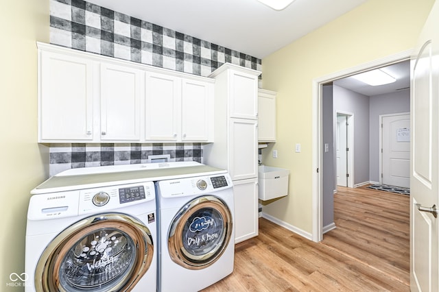 laundry room featuring cabinets, washer and clothes dryer, and light hardwood / wood-style floors