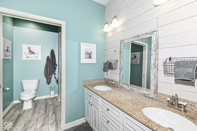 bathroom featuring vanity, hardwood / wood-style floors, wood walls, and toilet