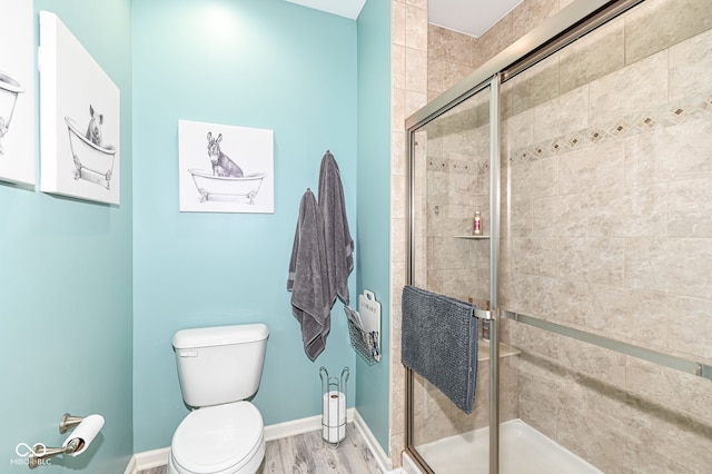 bathroom with wood-type flooring, a shower with shower door, and toilet