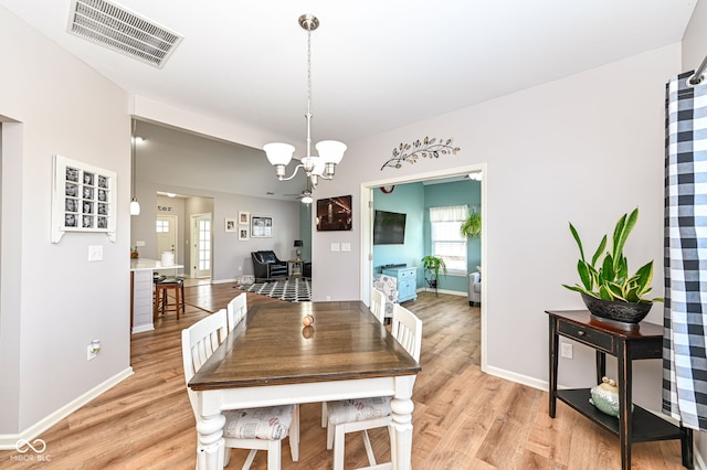 dining space with light hardwood / wood-style floors and a chandelier