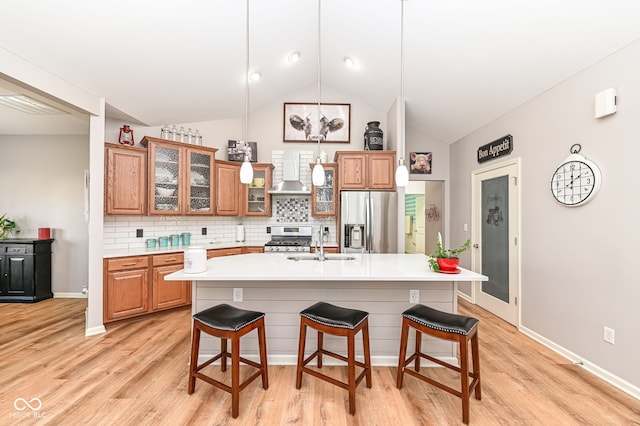 kitchen with a kitchen island with sink, sink, wall chimney exhaust hood, and appliances with stainless steel finishes