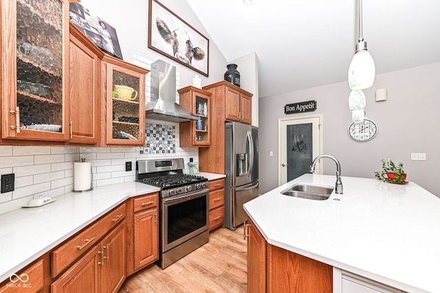 kitchen featuring sink, pendant lighting, stainless steel appliances, decorative backsplash, and wall chimney range hood