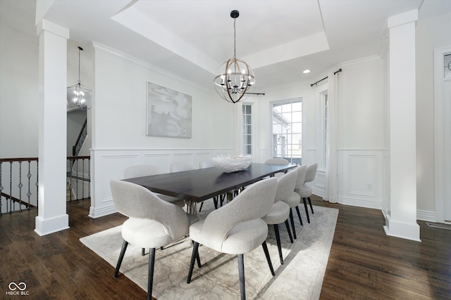 dining area with a raised ceiling, dark hardwood / wood-style flooring, ornamental molding, and an inviting chandelier