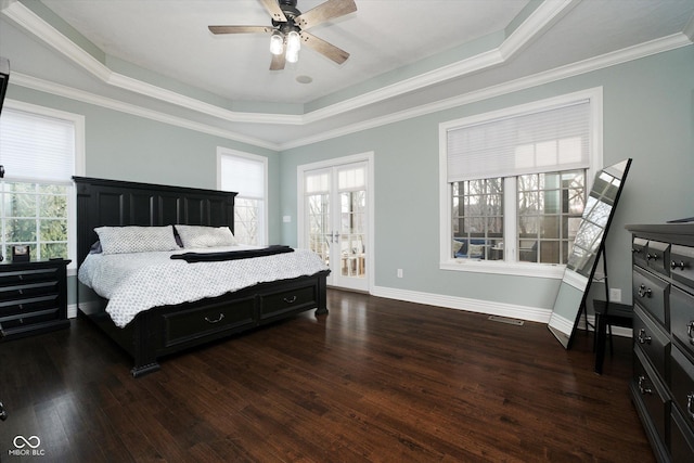 bedroom featuring dark wood-type flooring, a tray ceiling, multiple windows, and crown molding