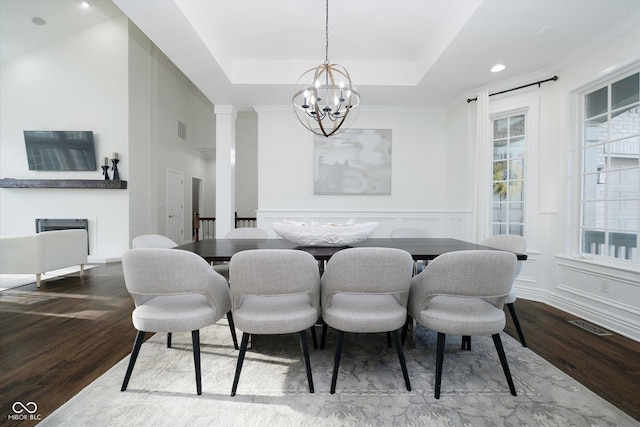 dining area with a notable chandelier, hardwood / wood-style flooring, ornamental molding, and a raised ceiling